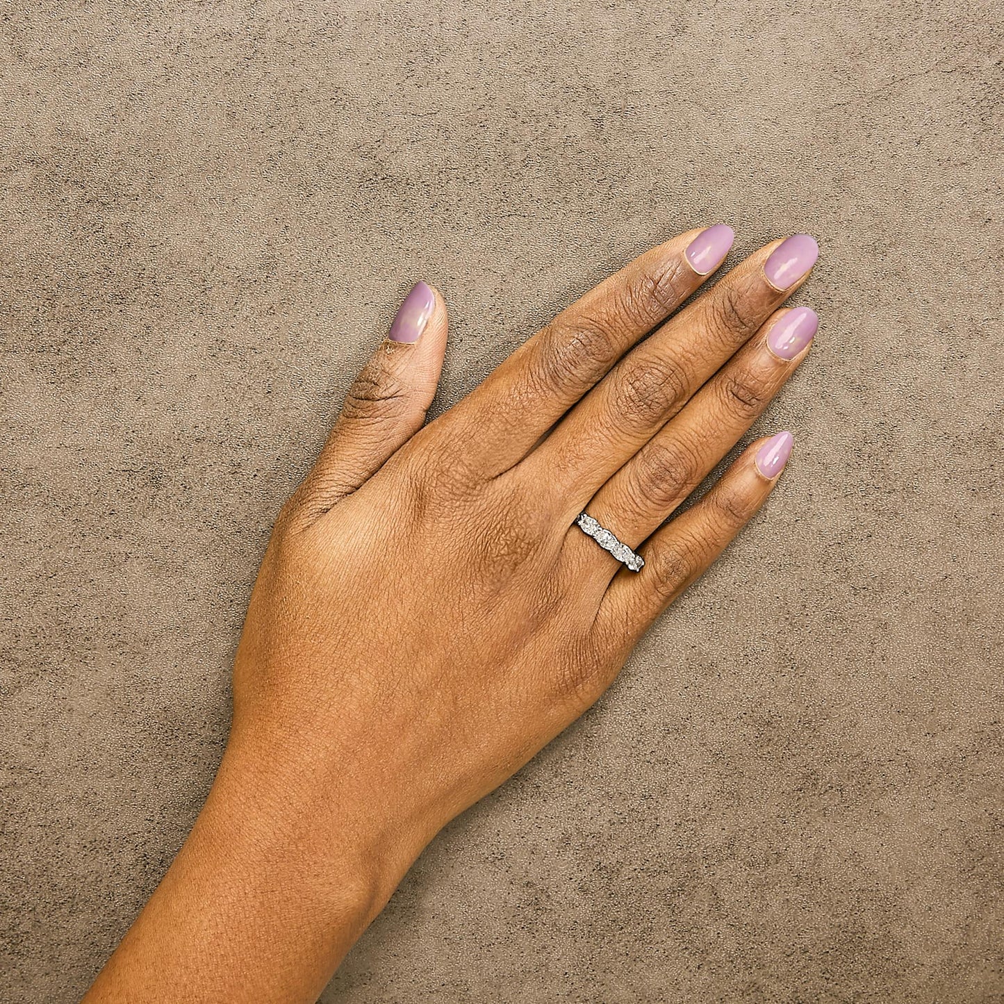 White metal ring with five oval-shaped white gemstones in shared prong setting, shown worn on a model's hand from a top angle.