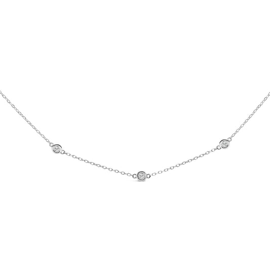 Close-up front view of a white metal necklace with round white gemstones in bezel settings evenly spaced along a delicate chain.