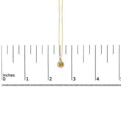 Close-up image of a yellow metal necklace with a round yellow gemstone pendant surrounded by smaller white gemstones, shown on a scale.