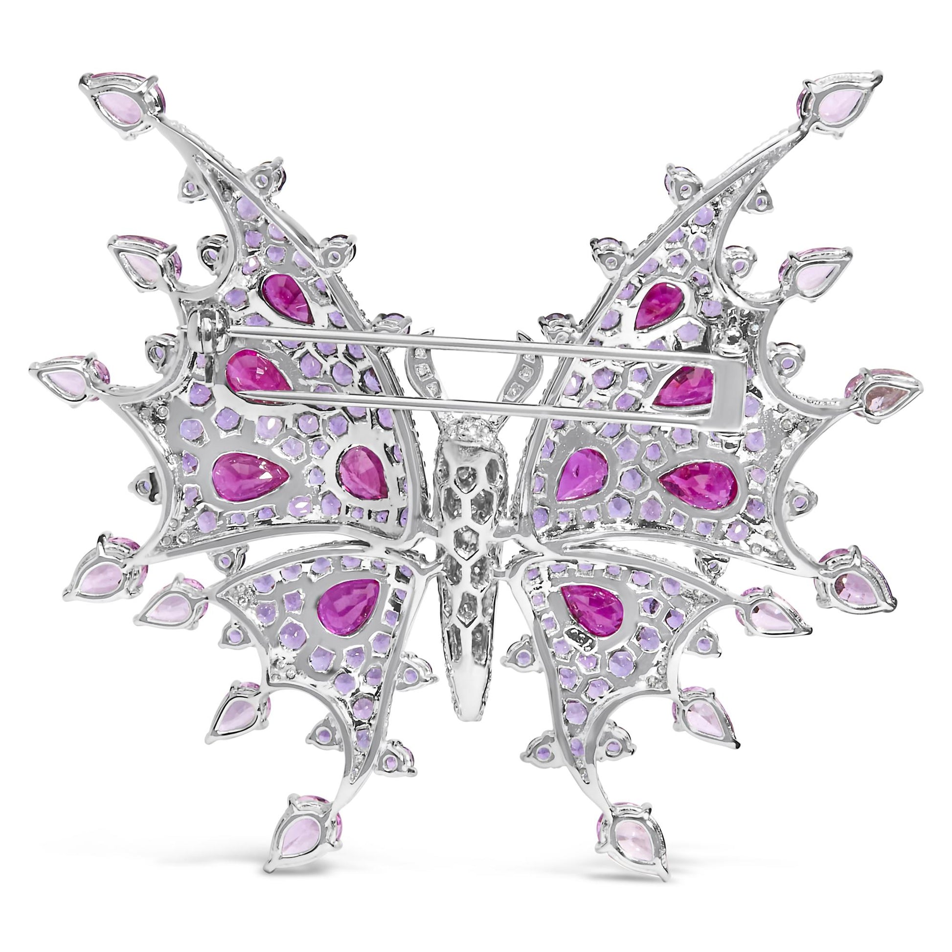 Back view of a white butterfly-shaped brooch with red pear-shaped gemstones, pink pear-shaped gemstones, purple round gemstones, and white round gemstones in pave setting, shown flat on a white background.