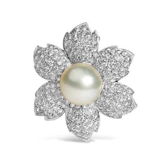 Brooch in flower shape with white metal petals pave set with round white gemstones and a central large white gemstone, front-facing angle.