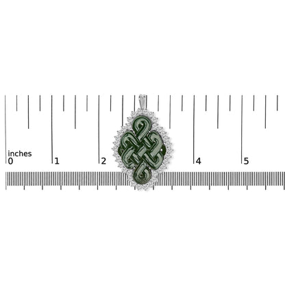 Top-down view of a white metal brooch with a green fantasy-shaped gemstone in the center, surrounded by a border of round white gemstones, placed on a ruler for size reference.