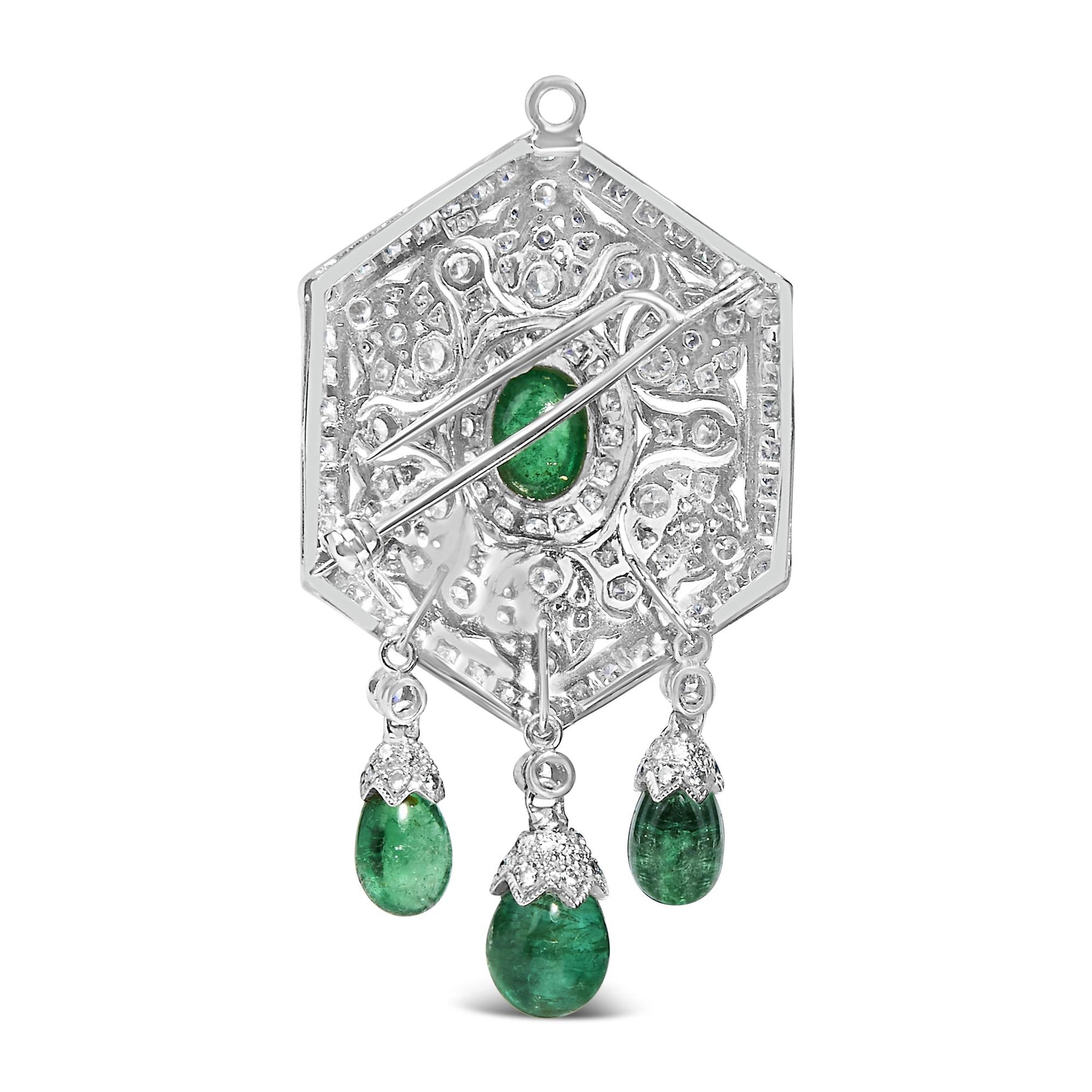 Back view of a white metal hexagonal brooch with intricate filigree, round white gemstones in pave setting, one oval green gemstone in bezel setting at the center, and three oval green gemstones hanging from the bottom.