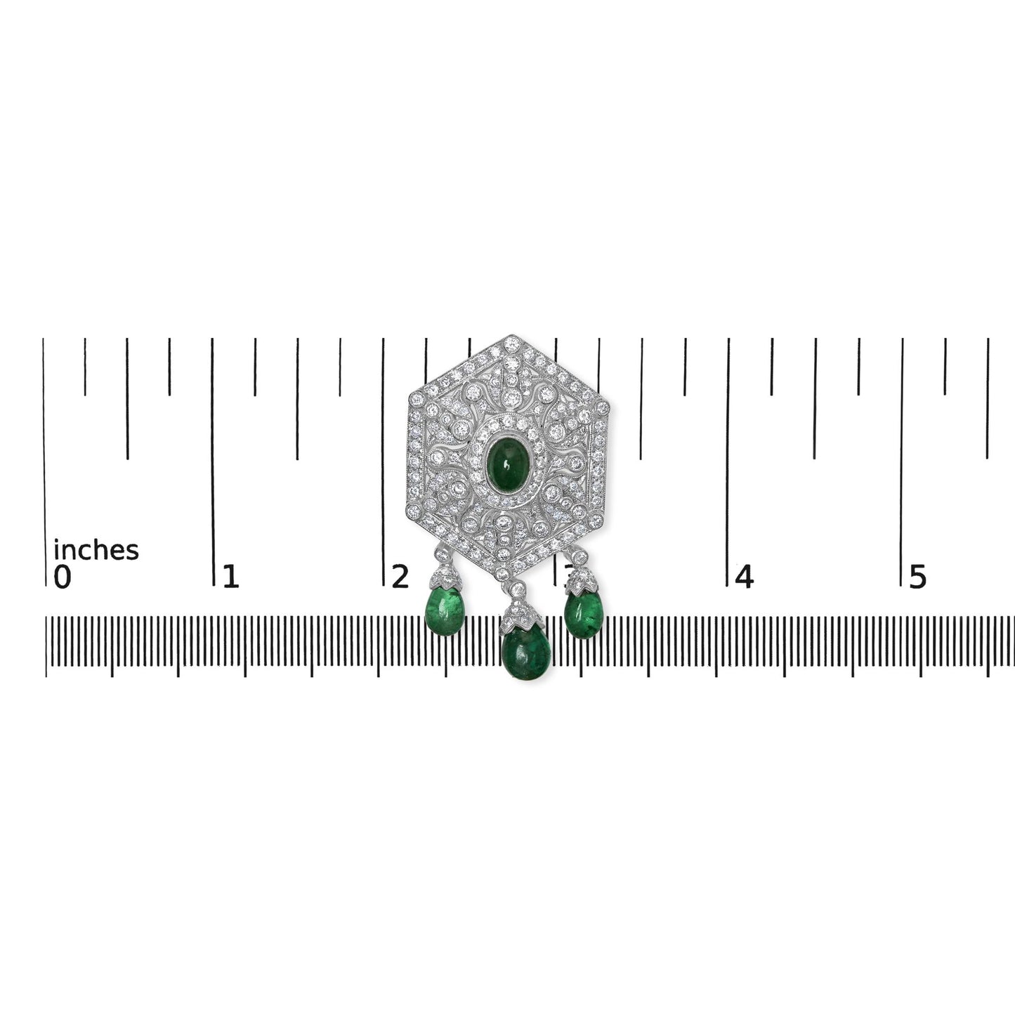 Top-down view of a white brooch with round and marquise shaped white gemstones in pave and prong settings, featuring a central oval green gemstone and three dangling green fantasy-shaped gemstones, placed on a ruler for size reference.