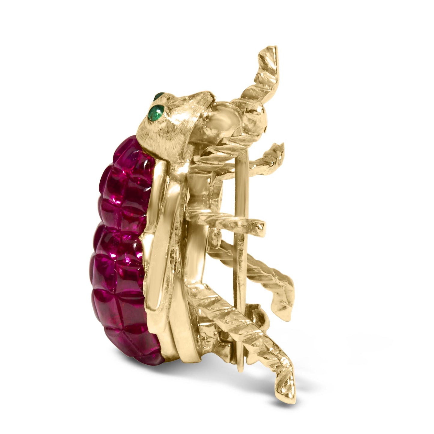 Yellow metal brooch shaped like a bug, side angle view showing textured legs and pin back, decorated with red cushion-shaped gemstones and small green round gemstones.