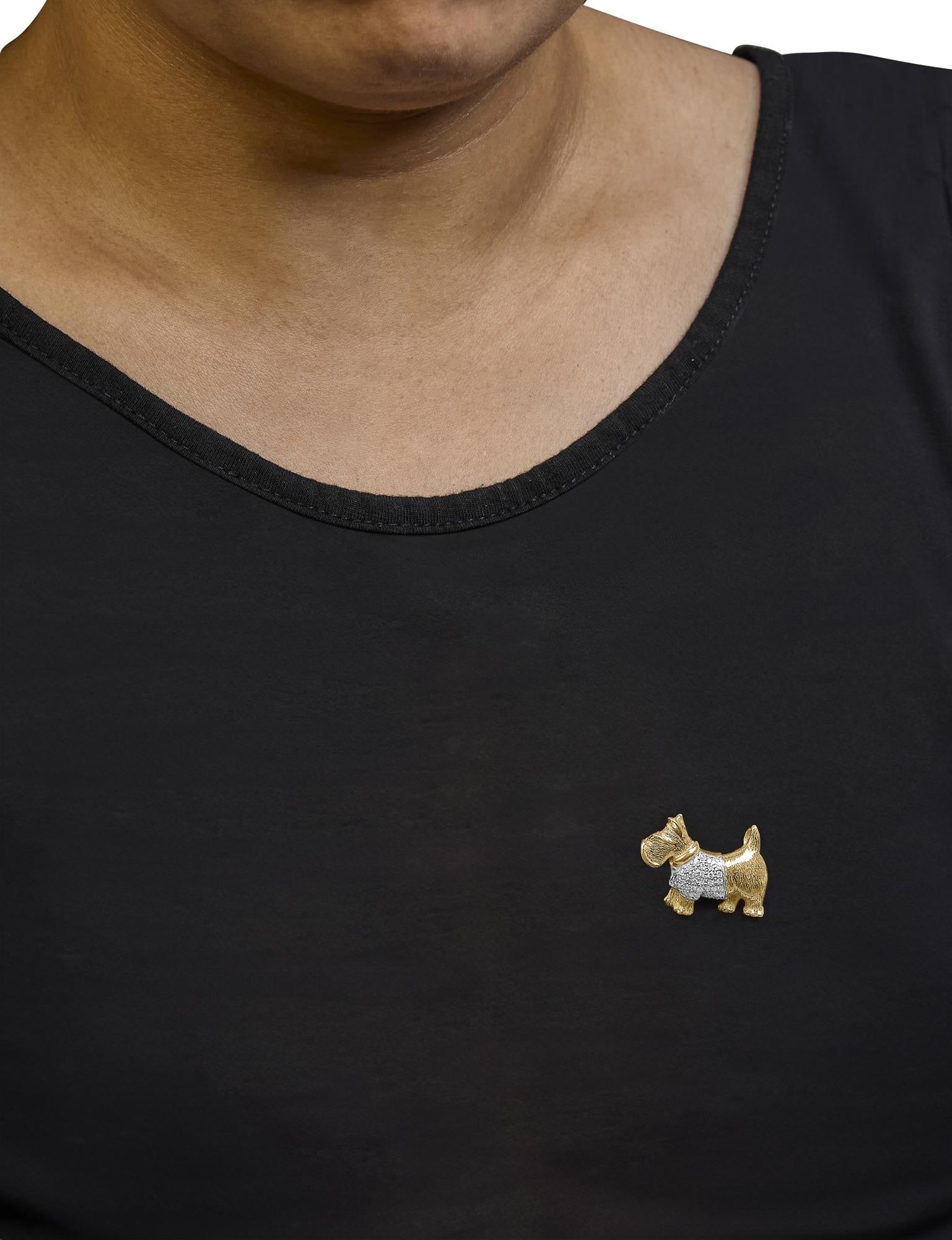 Brooch shaped like a small dog with a textured yellow metal body and a white gemstone pave setting on its midsection, worn on a black shirt on a model, front-facing view.
