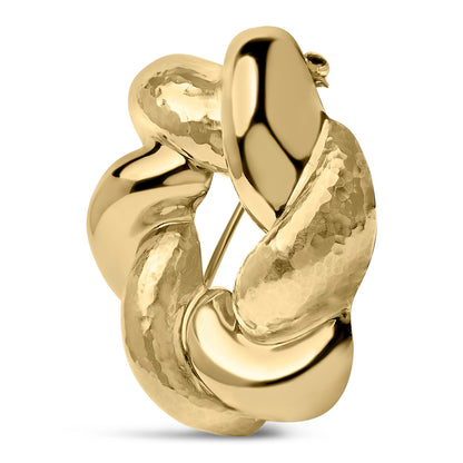 Close-up front angle of a yellow metal twisted and textured circular brooch.