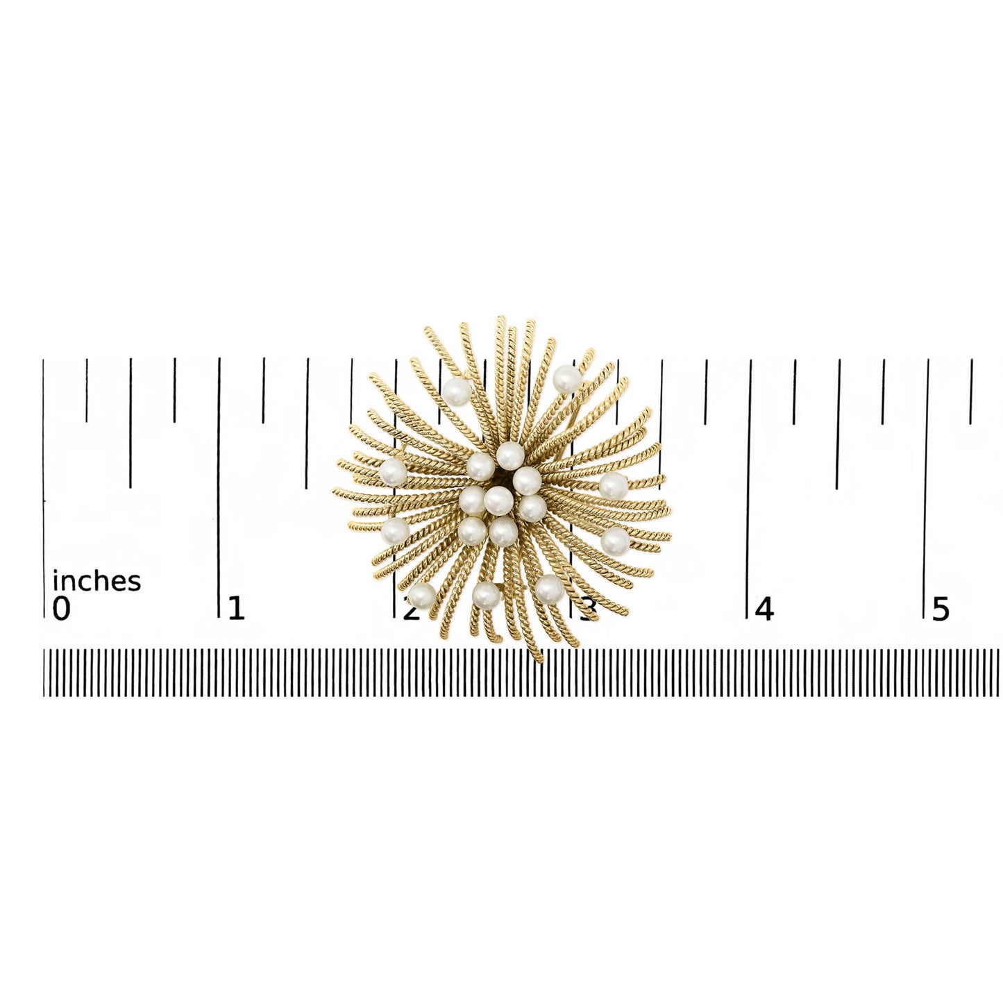 Brooch shaped like a swirling floral burst with textured yellow metal strands and scattered white gemstones, shown on a scale from a top-down angle.