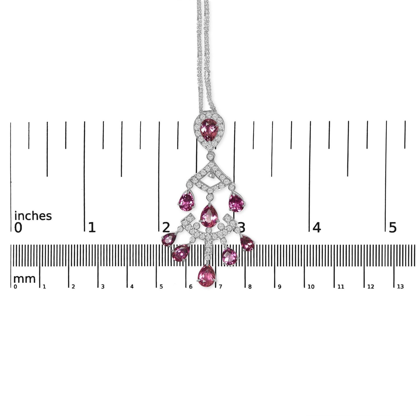 White metal necklace with pink pear-shaped gemstones and round white gemstones in prong settings, shown flat against a ruler for size reference, photographed from above.