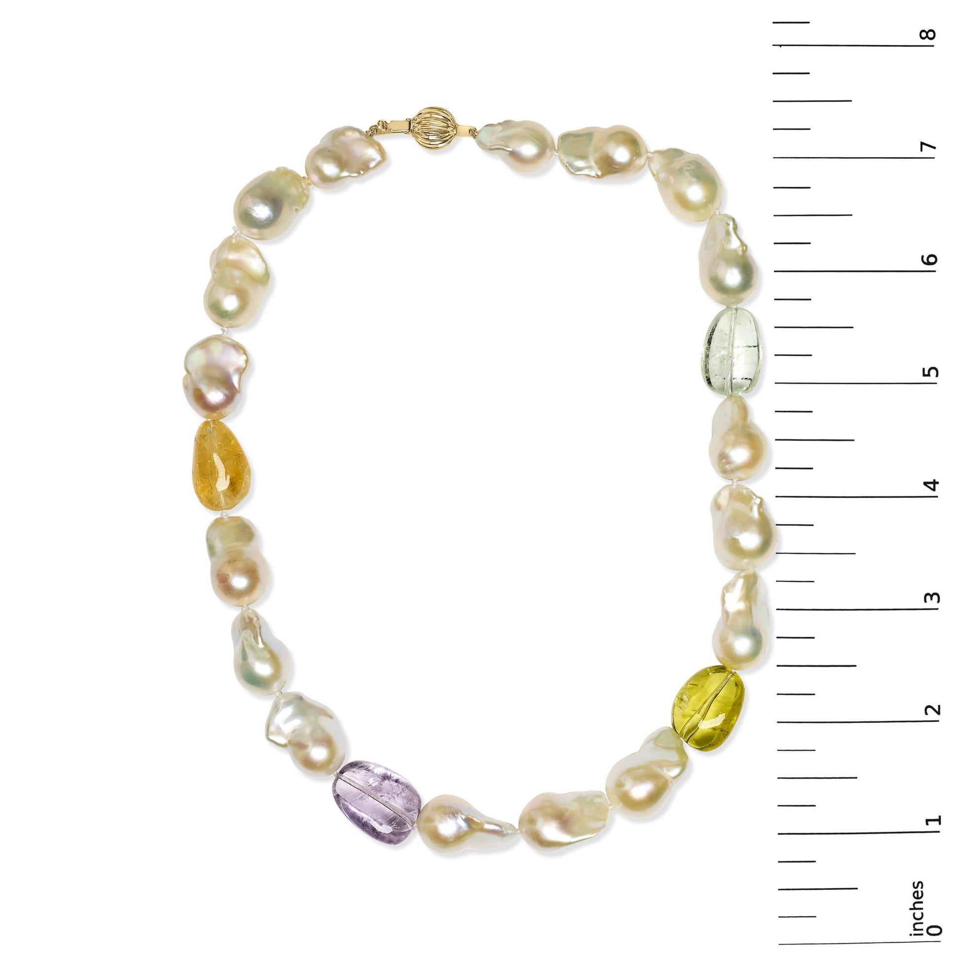Top-down view of a yellow metal necklace with irregular white pearls and three yellow gemstones, shown on a ruler for size reference.