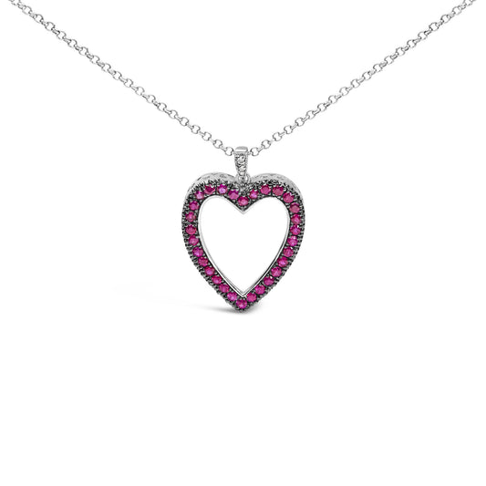 Front-facing shot of a white metal heart-shaped necklace pendant adorned with round red gemstones in shared prong setting and a few round white gemstones in pave setting on the bail.