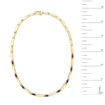 Yellow and white metal necklace with alternating red oval gemstones and white round gemstones in prong settings, shown flat on a white background next to a ruler for scale.