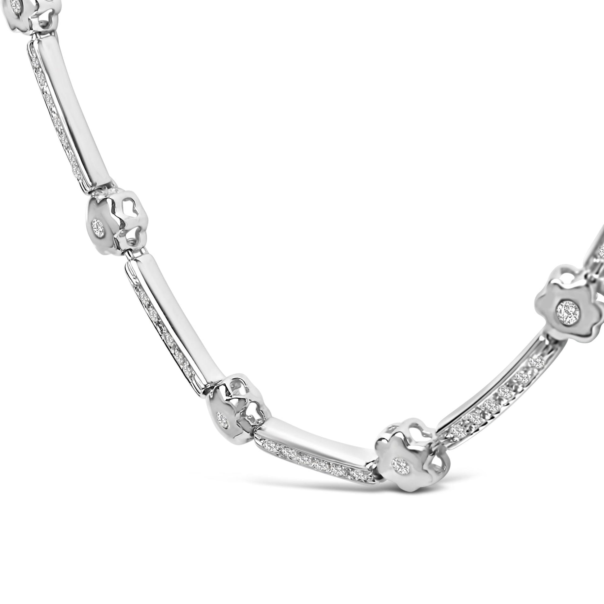 Close-up angled shot of a white metal necklace featuring alternating bar segments with small white gemstones and flower-shaped links each set with a single white gemstone.