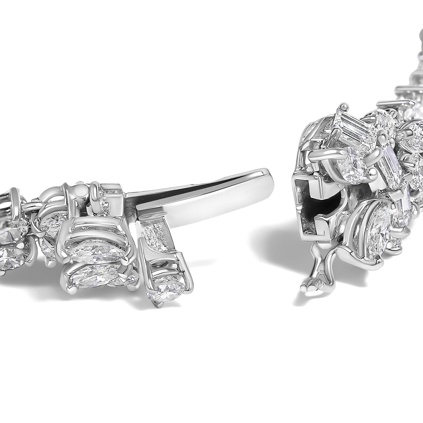 Close-up of a white metal jewelry bracelet clasp with round, baguette, and marquise-shaped white gemstones set along the band, shown from a side angle.