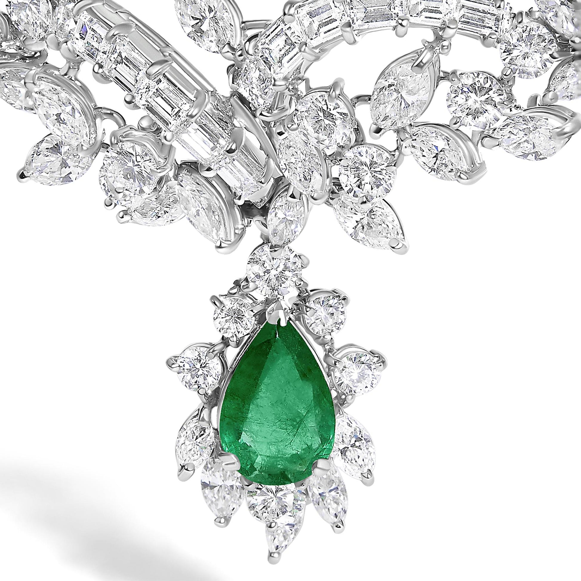 Close-up angled view of a white metal jewelry set featuring a large pear-shaped green gemstone pendant surrounded by multiple round and marquise-shaped white gemstones, along with baguette-shaped white gemstones in the chain.