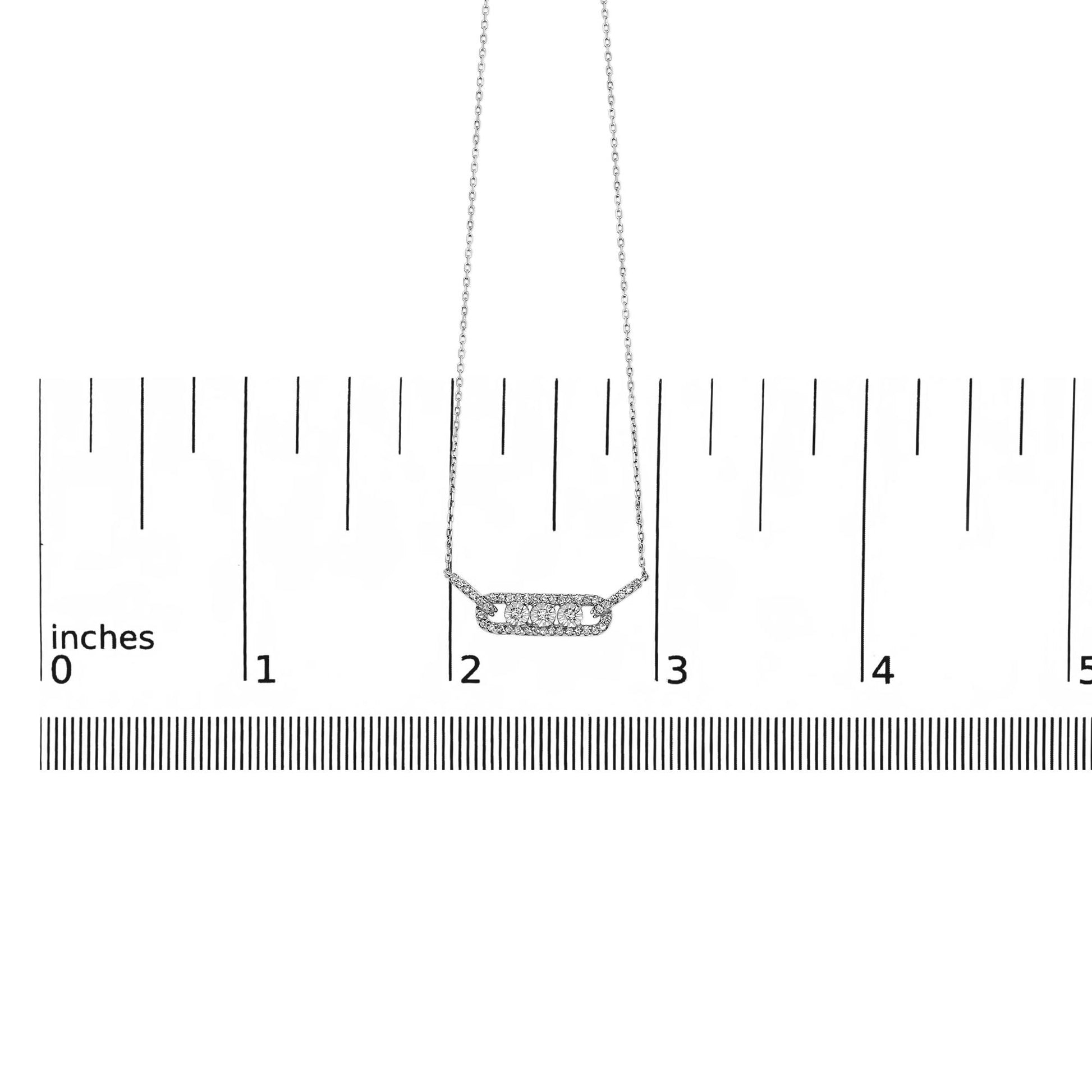 White metal necklace with a horizontal bar pendant featuring three round white gemstones in miracle setting surrounded by smaller round white gemstones in prong setting, shown on a ruler scale from a front angle.