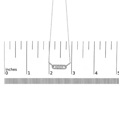 White metal necklace with a horizontal bar pendant featuring three round white gemstones in miracle setting surrounded by smaller round white gemstones in prong setting, shown on a ruler scale from a front angle.