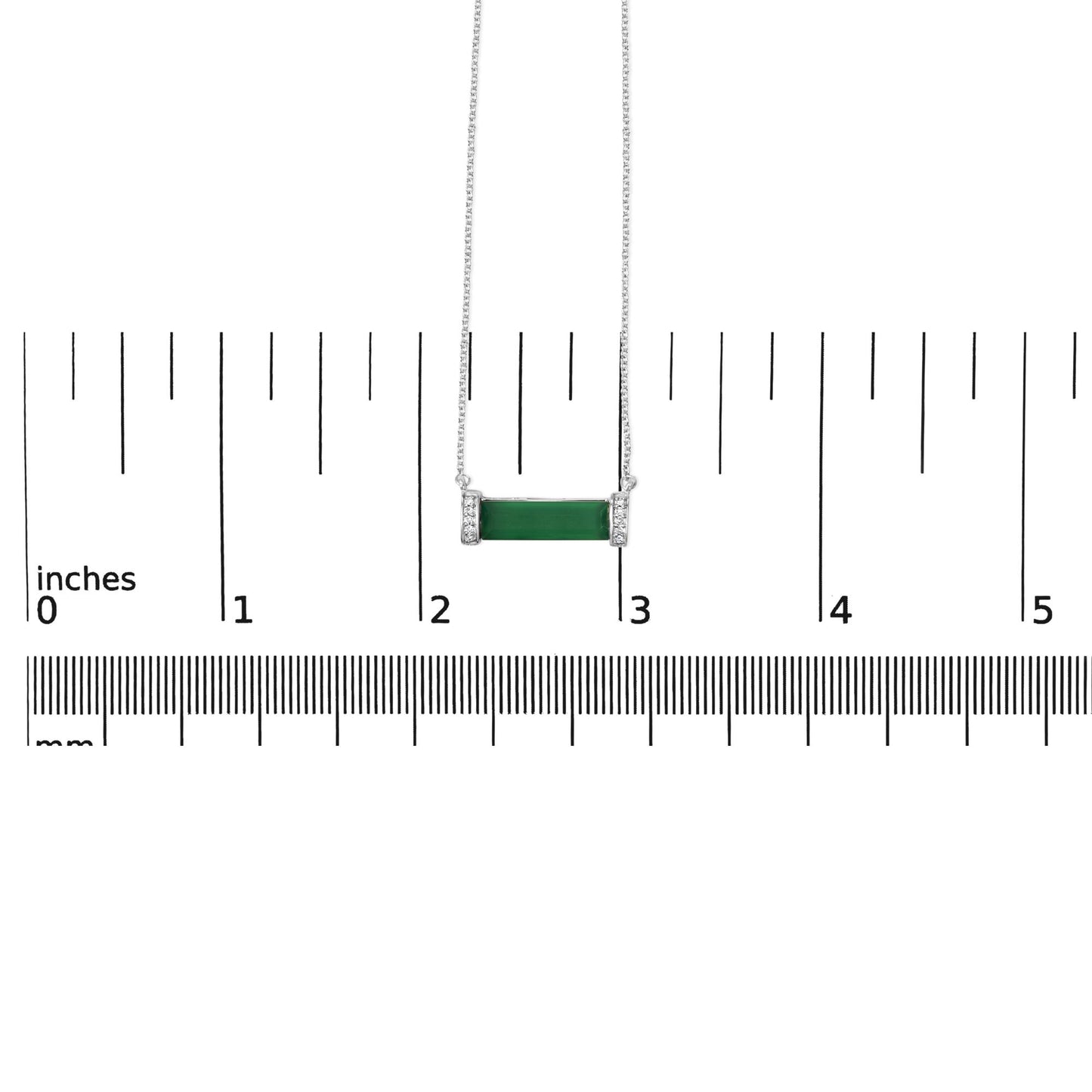White necklace with a horizontal green baguette-shaped gemstone in the center, flanked by two vertical sections with small round white gemstones in pave setting, shown from the front on a scale.