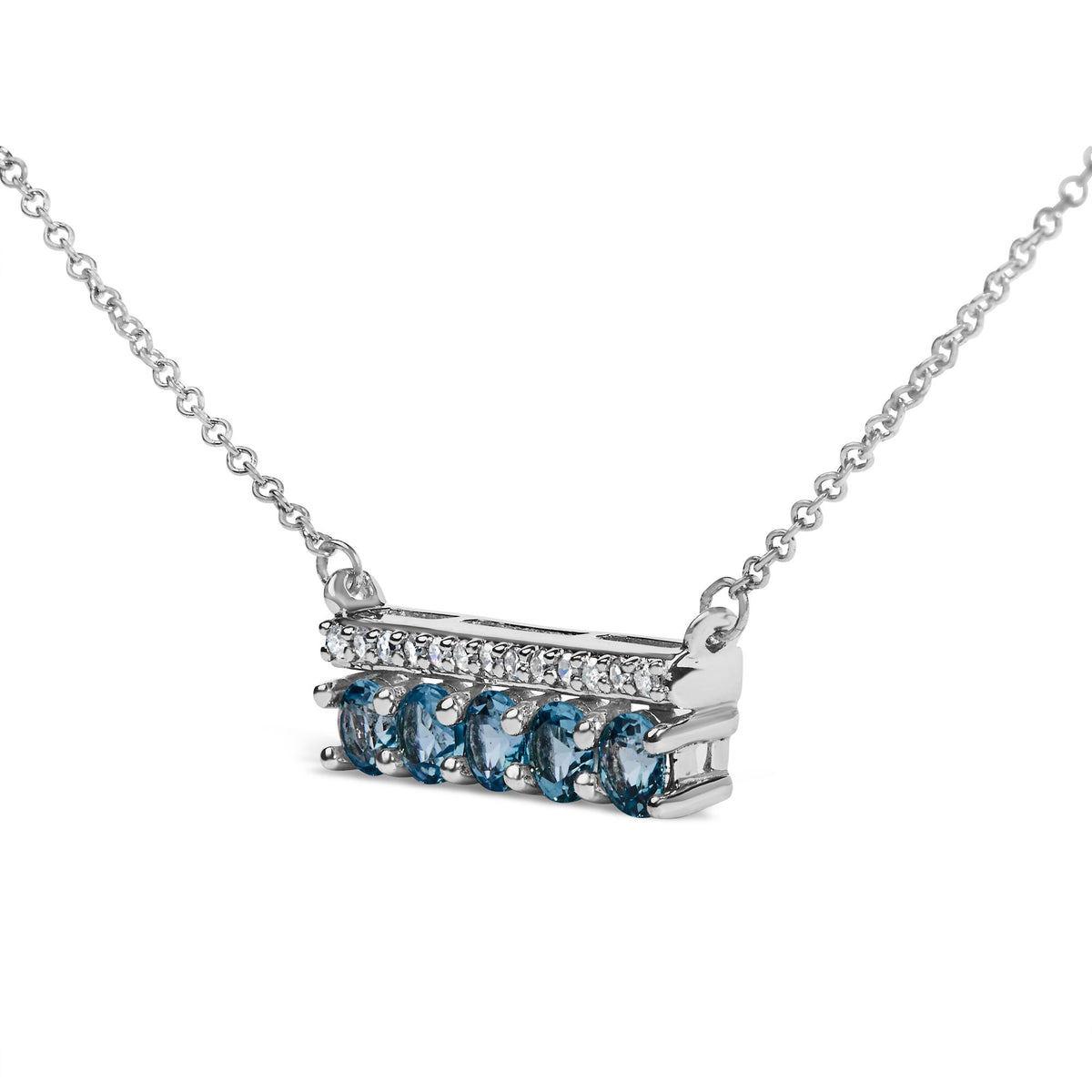 Close-up front angled view of a white necklace pendant with a row of round blue gemstones set in prongs beneath a row of small round white gemstones in pave setting, attached to a white chain.