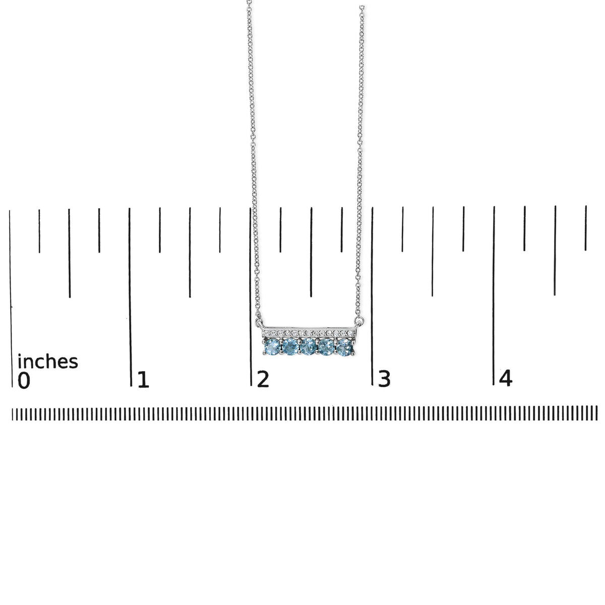 Close-up front view of a white necklace shown on a scale. The pendant is a horizontal bar with five round blue gemstones set in prongs on the bottom and a row of small round white gemstones in pave setting on the top, hanging from a delicate chain.
