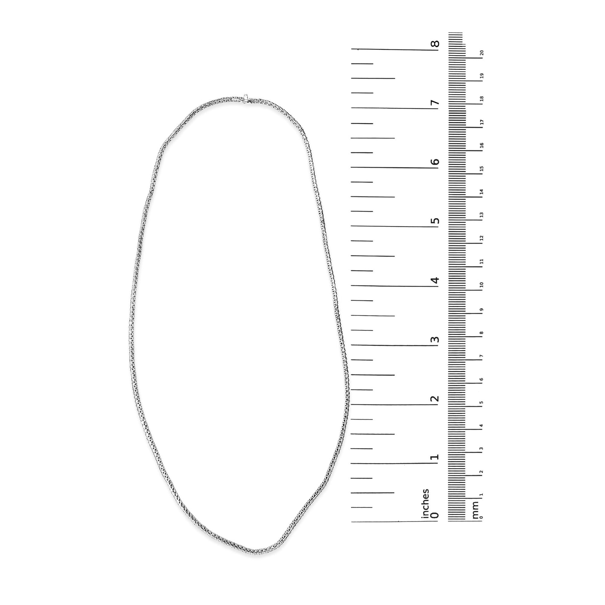 White metal necklace with round white gemstones in prong settings, shown flat next to a ruler on a white background, top-down angle.