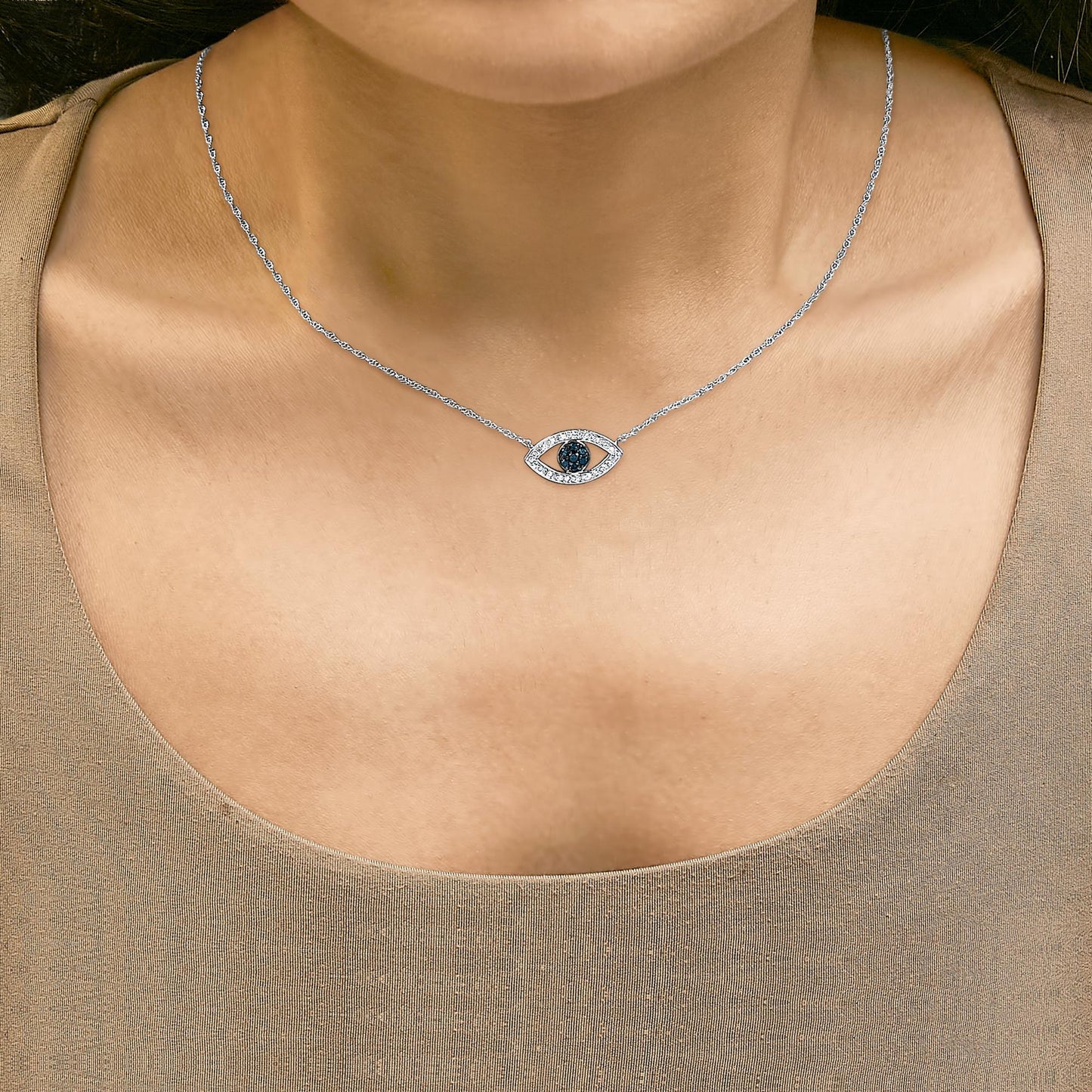 Close-up front view of a model wearing a white metal necklace with an eye-shaped pendant featuring blue round gemstones in the center and white round gemstones surrounding it.