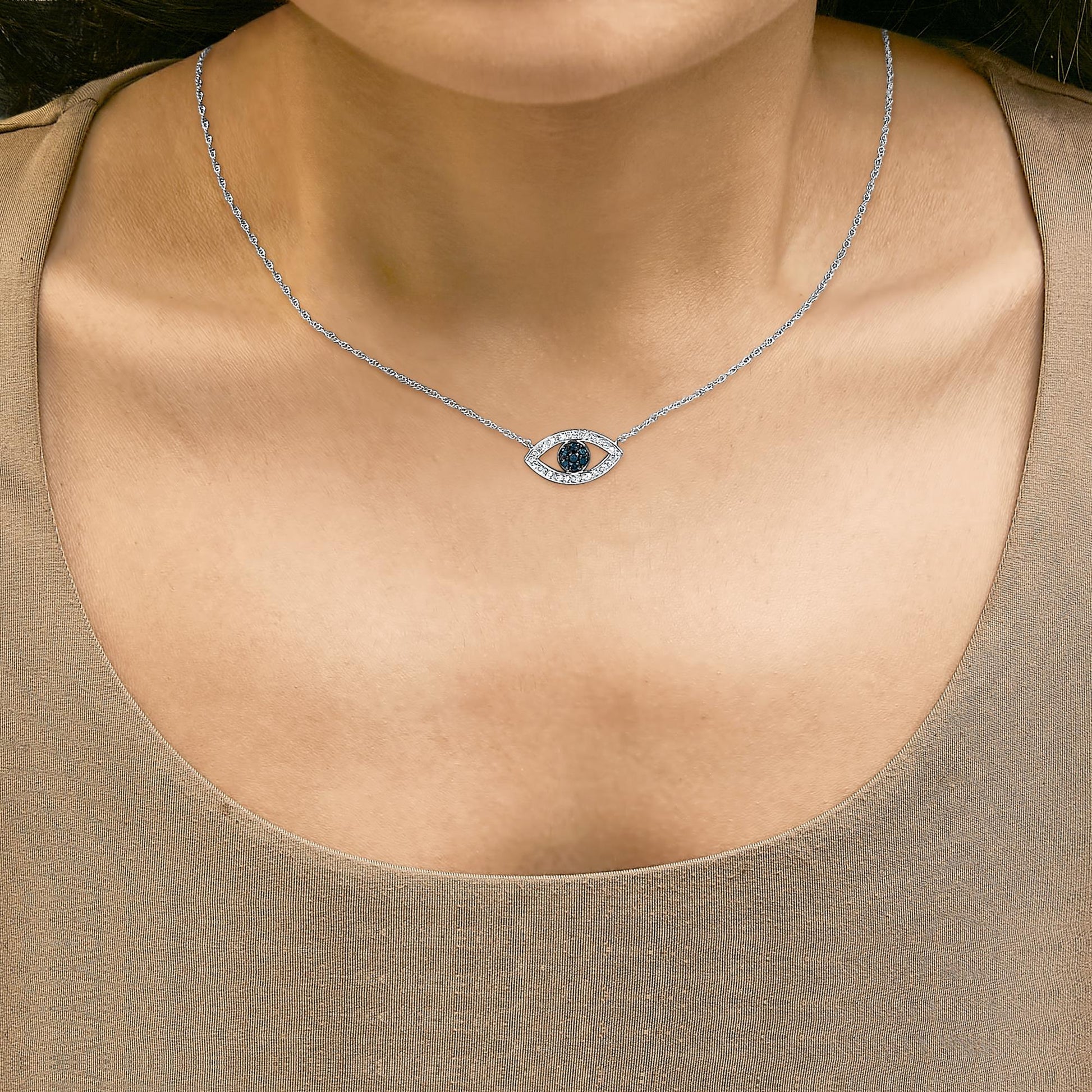 Close-up front view of a model wearing a white metal necklace with an eye-shaped pendant featuring blue round gemstones in the center and white round gemstones surrounding it.