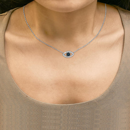 Close-up front view of a model wearing a white metal necklace with an eye-shaped pendant featuring blue round gemstones in the center and white round gemstones surrounding it.
