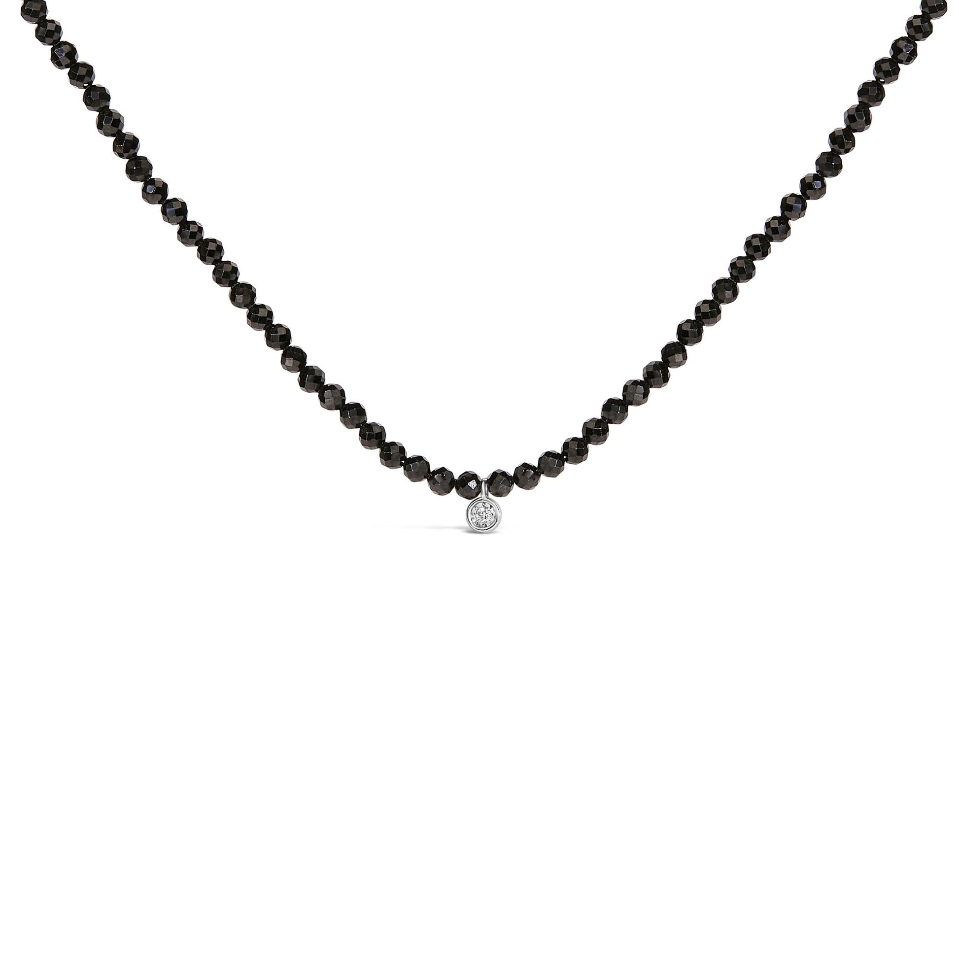 Close-up front view of a white necklace with round black gemstones forming the chain and a single round white gemstone pendant in the center.