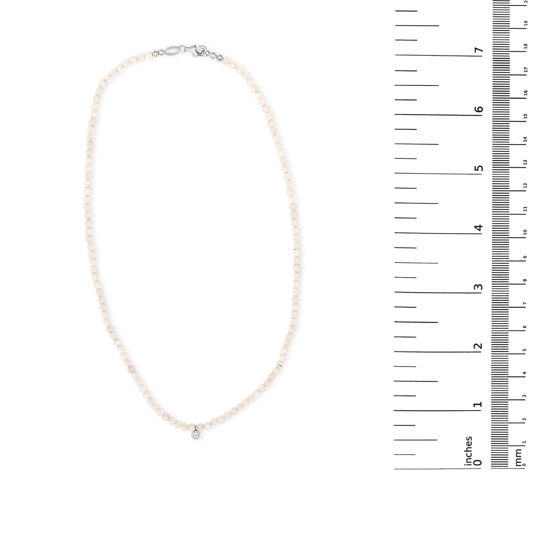 White gemstone beaded necklace with a single white round gemstone pendant shown on a scale, top-down angle.