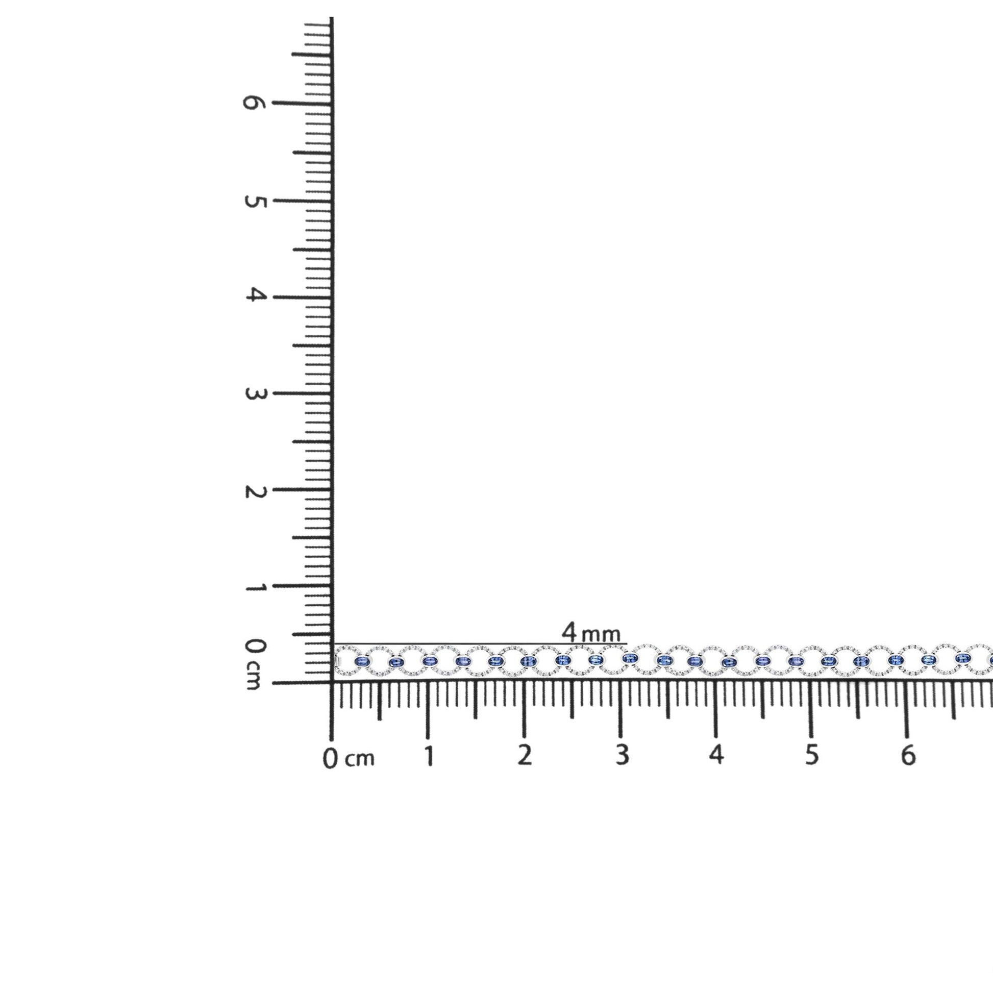 White bracelet with round white gemstones in prong setting and oval blue gemstones in bezel setting, displayed horizontally on a ruler for size reference, shot from above.