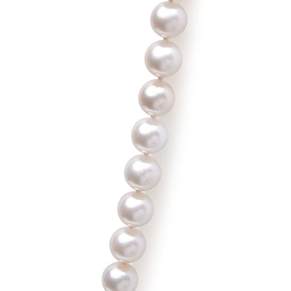 Close-up angled view of a necklace featuring a strand of round white pearls against a white background.
