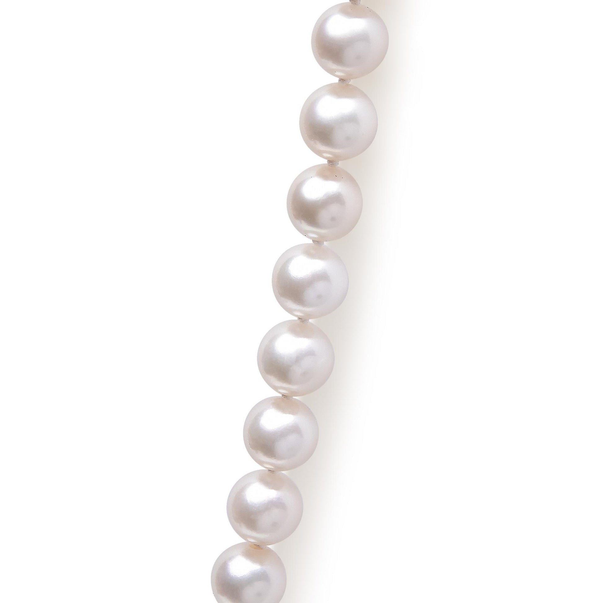 Close-up side view of a yellow metal necklace with round white pearls.