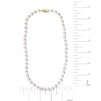 Top-down view of a necklace shown on a scale, featuring round white beads with a yellow metal clasp.