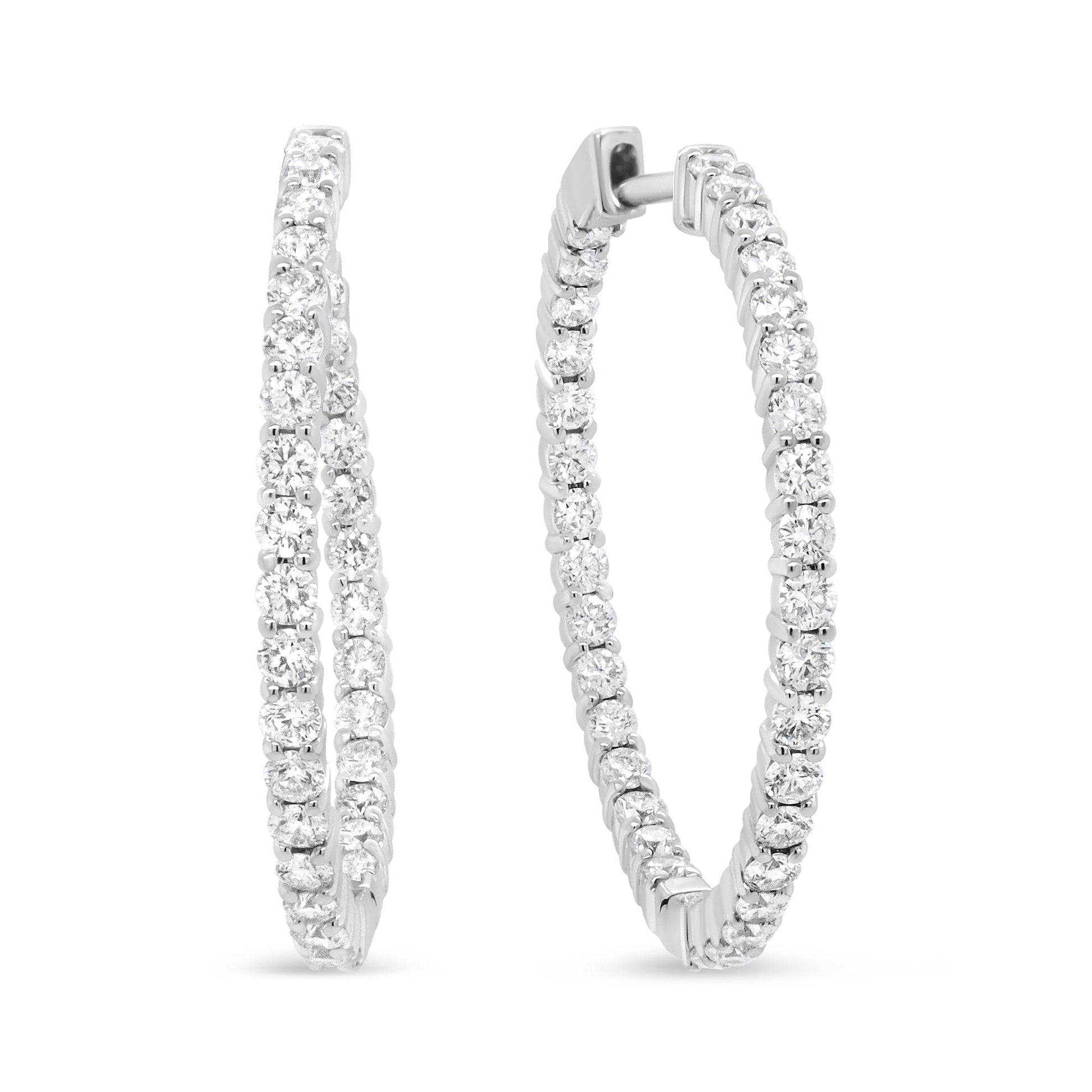 Pair of white metal hoop earrings with round white gemstones in prong settings, shown from a front angled view.