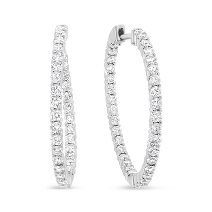 Pair of white metal hoop earrings with round white gemstones in prong settings, shown from a front angled view.