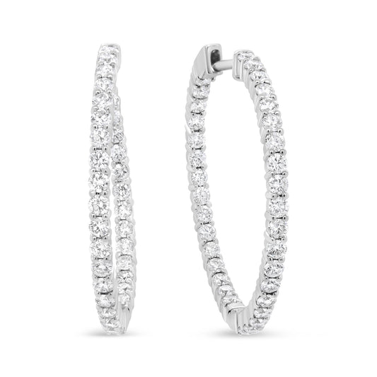 Pair of white metal hoop earrings with round white gemstones in prong settings, shown from a front angled view.