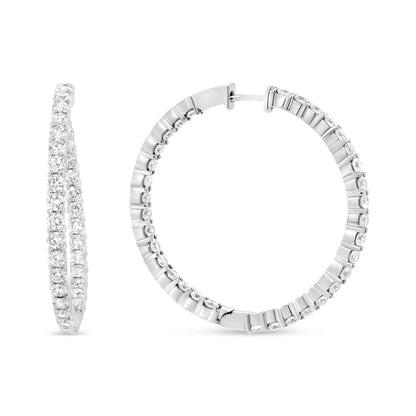 Close-up front and side view of white metal hoop earrings set with round white gemstones in prong settings.