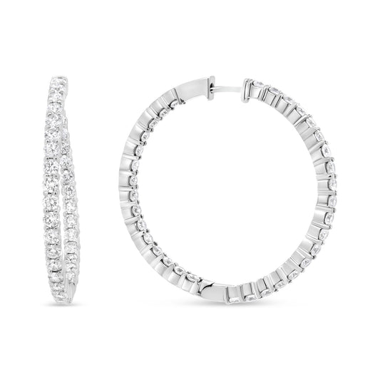 Close-up front and side view of white metal hoop earrings set with round white gemstones in prong settings.