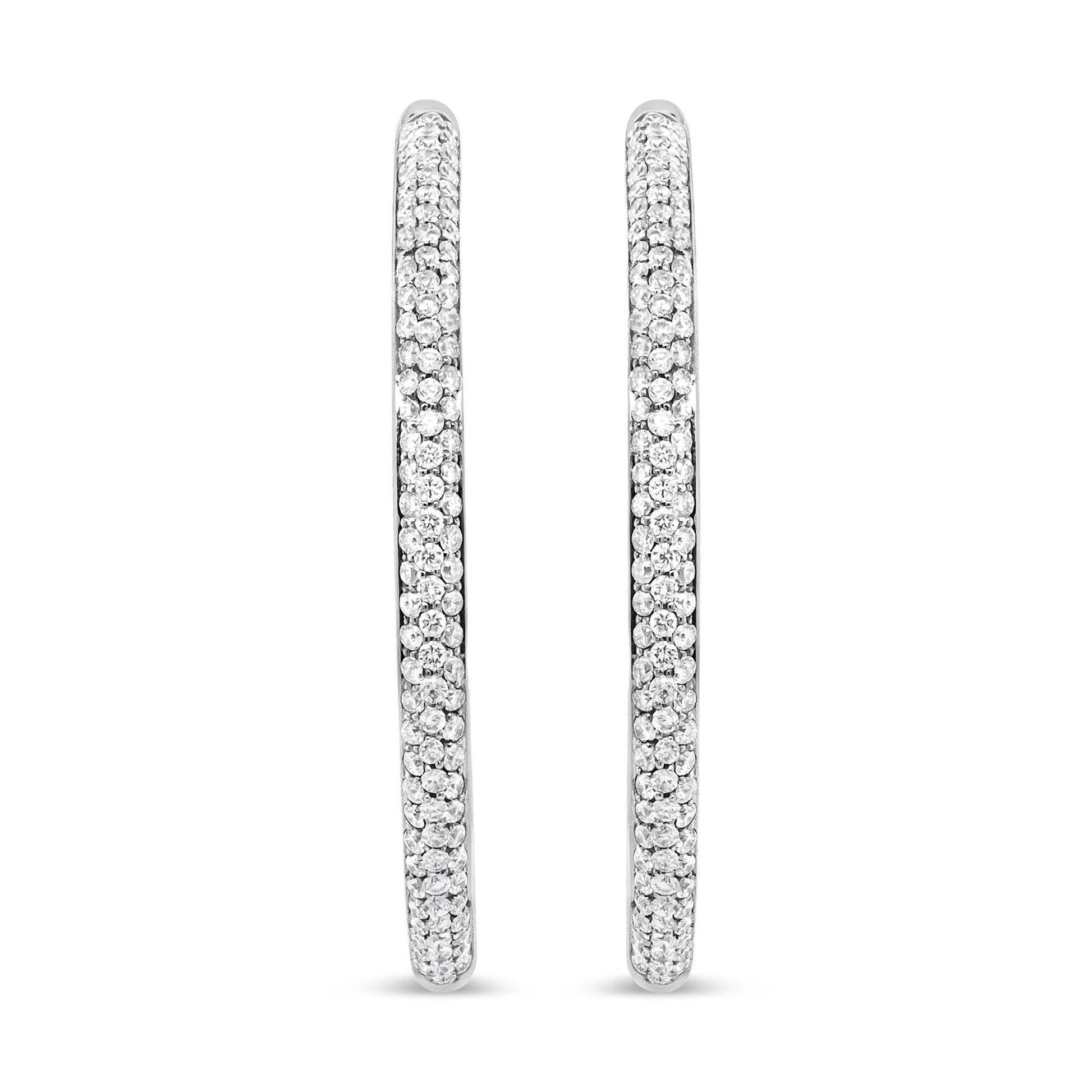 Pair of white metal hoop earrings encrusted with small round white gemstones in prong setting, shown from a front angle.