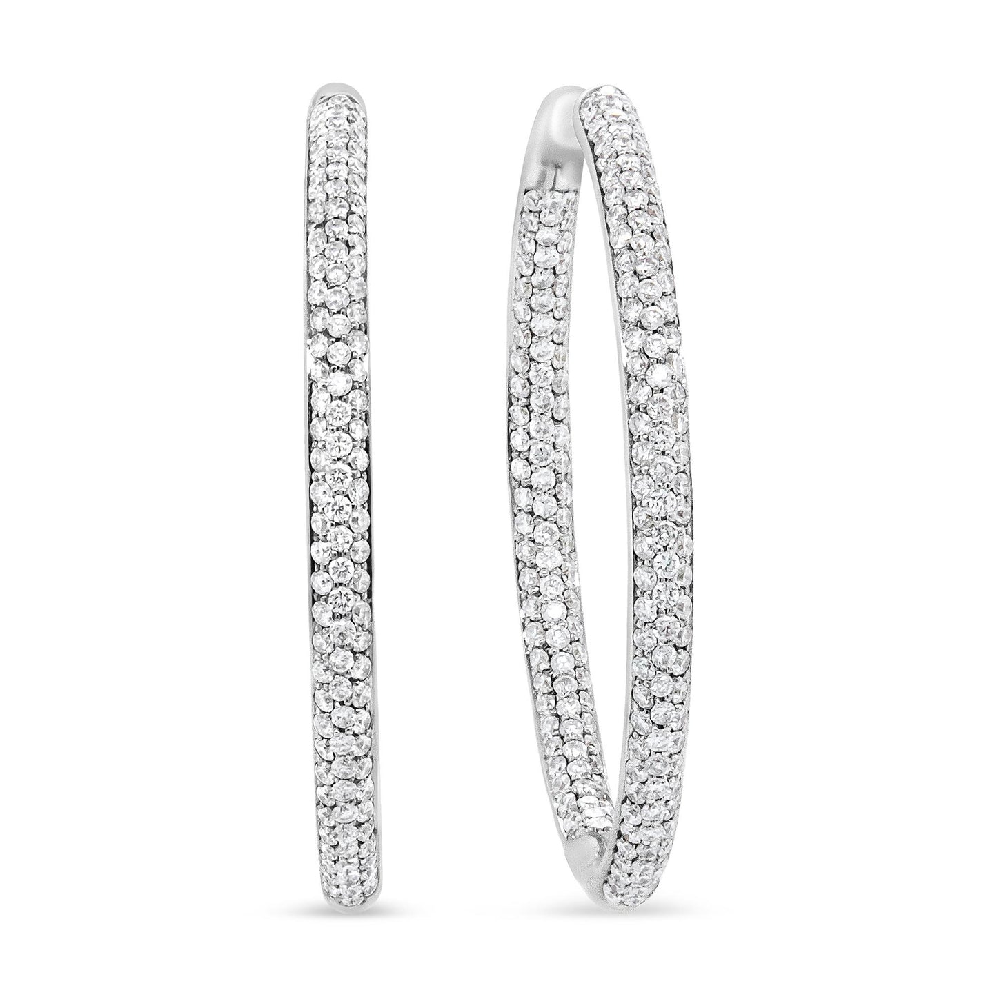 Close-up front and side view of white metal hoop earrings with round white gemstones in prong settings covering the outer surface.