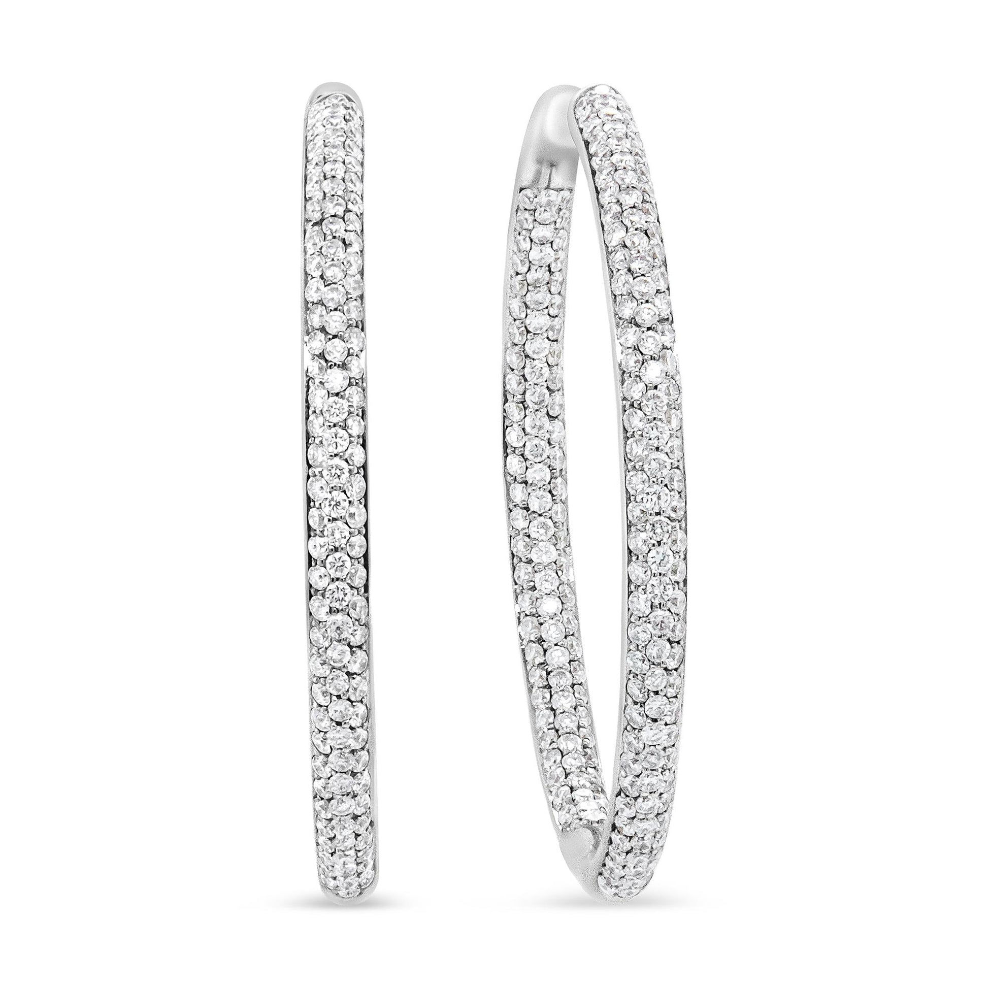 Close-up front and side view of white metal hoop earrings with round white gemstones in prong settings covering the outer surface.