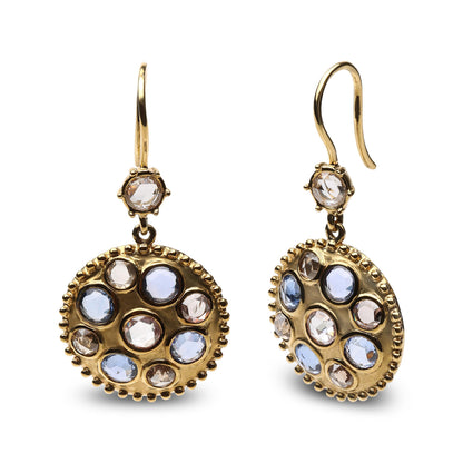 Pair of yellow metal earrings with round blue and brown gemstones and white gemstones in bezel settings, shown from a front and angled side view.