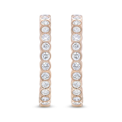 Front-facing close-up of a pair of rose-colored hoop earrings set with round white gemstones in bezel settings along the outer edge.