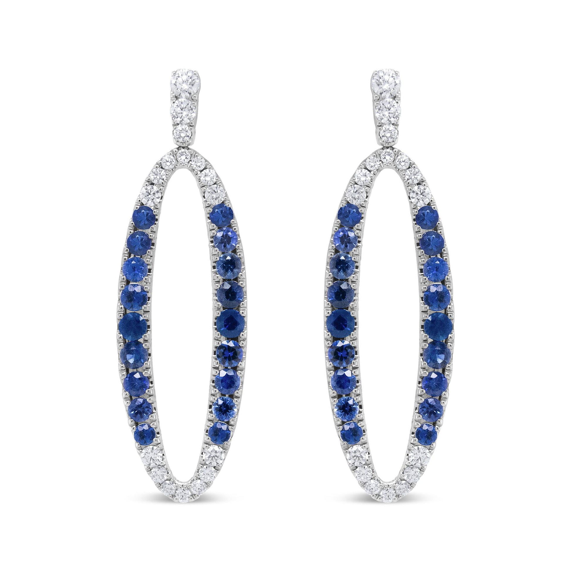 Front view of white metal oval-shaped earrings with alternating white and blue gemstones in prong settings.