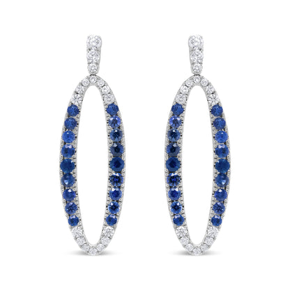 Front view of white metal oval-shaped earrings with alternating white and blue gemstones in prong settings.