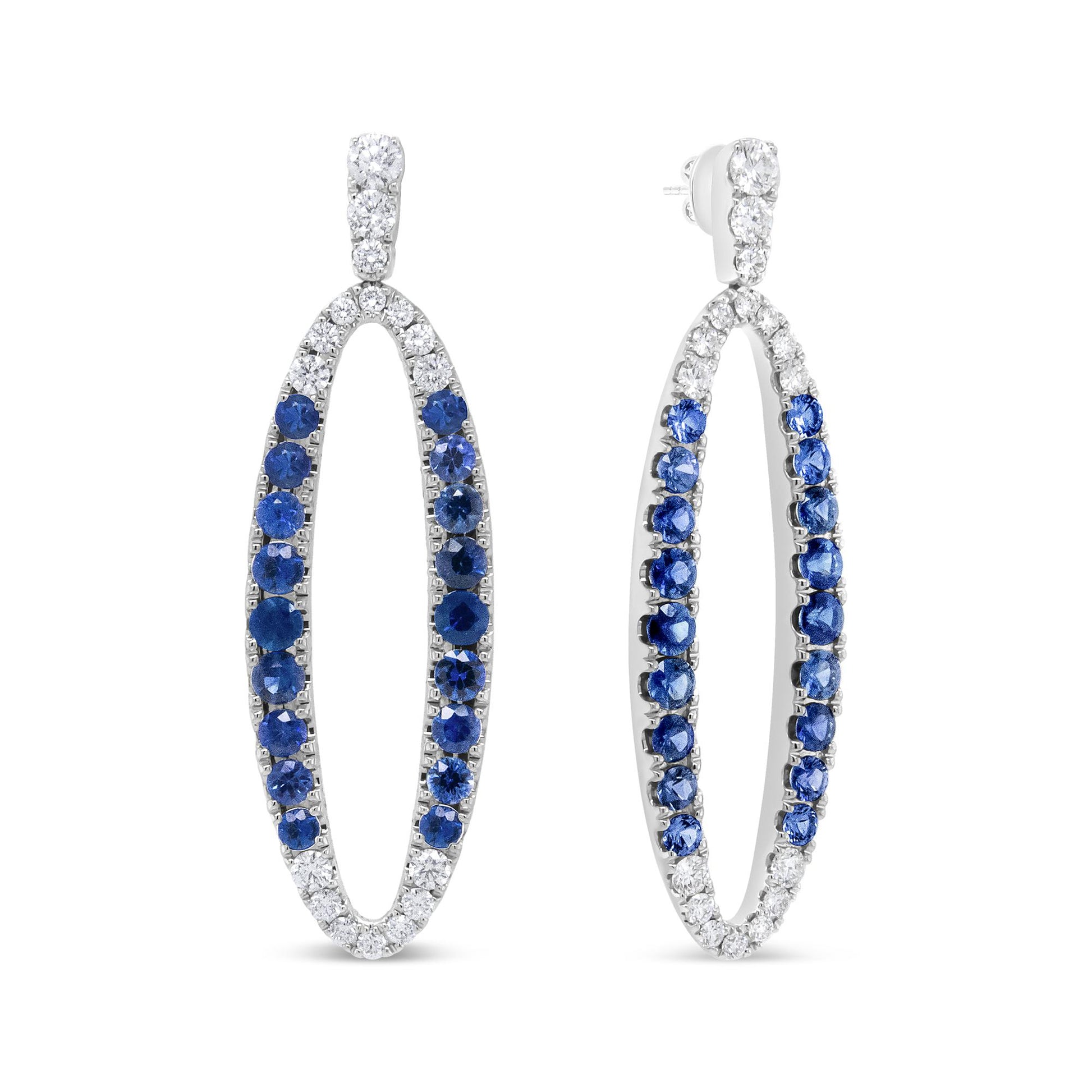 Pair of white metal oval hoop earrings with round prong-set white and blue gemstones, shown from a front and angled side view.