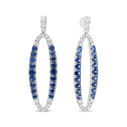 Pair of white metal oval hoop earrings with round prong-set white and blue gemstones, shown from a front and angled side view.