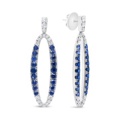 White metal oval-shaped earrings with alternating white and blue gemstones in prong settings, shown from front and side angles.