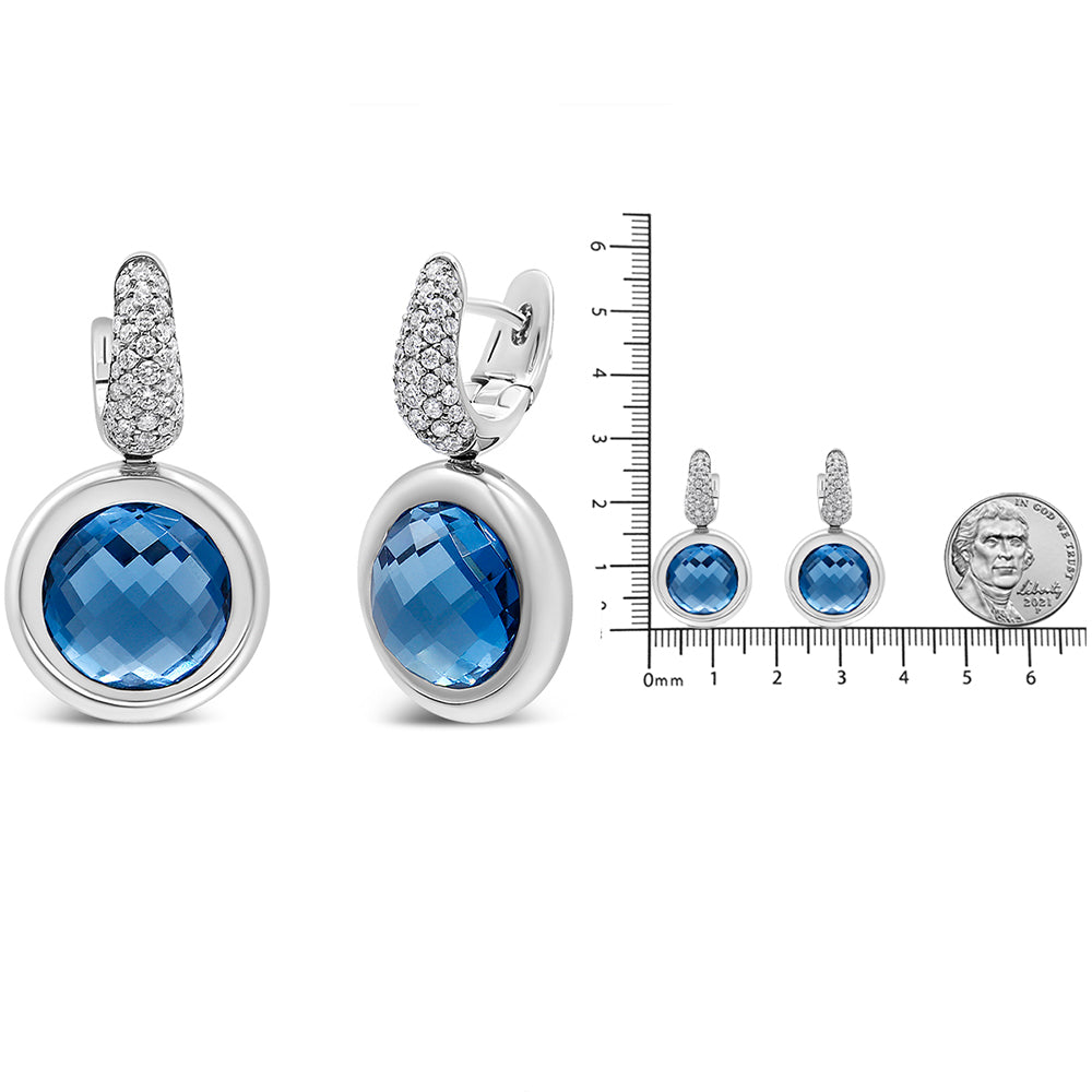 Front and side view of white metal earrings with round blue gemstones in bezel setting, topped with pavé-set white gemstones, shown next to a ruler and coin for size reference.